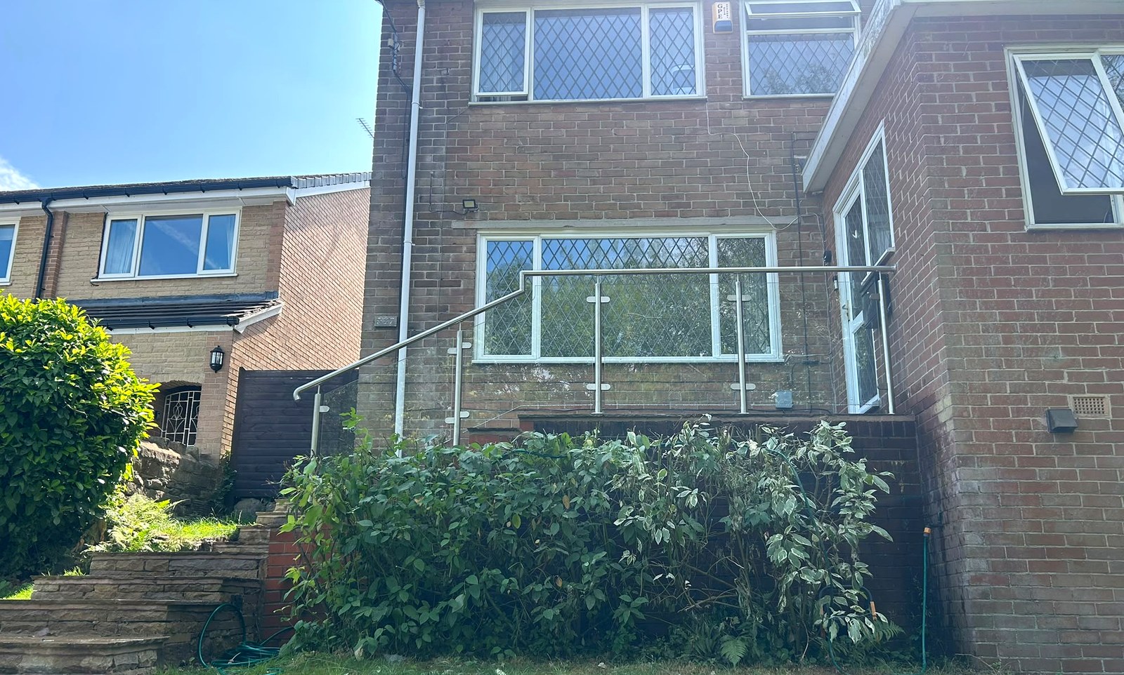 Stainless steel and glass balustrade running along a raised terrace above the garden, Sheffield